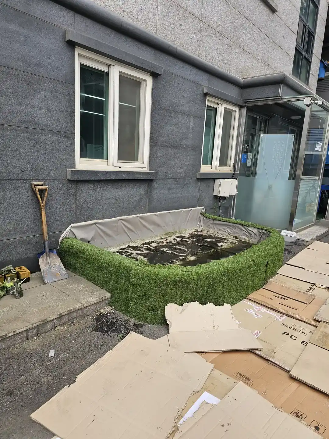 삽과 작업 도구가 놓인 연못 틀 시공 전 현장