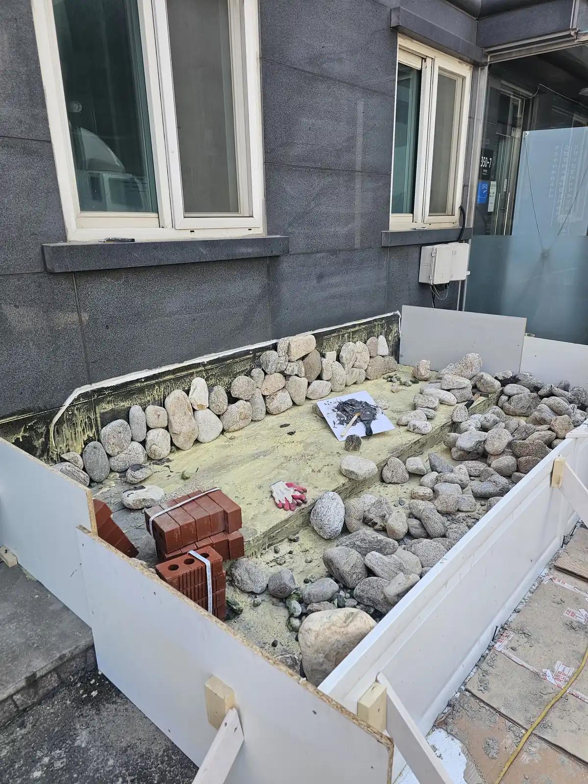 틀 안에 돌과 벽돌을 채우는 연못 시공 중 돌 쌓기 단계