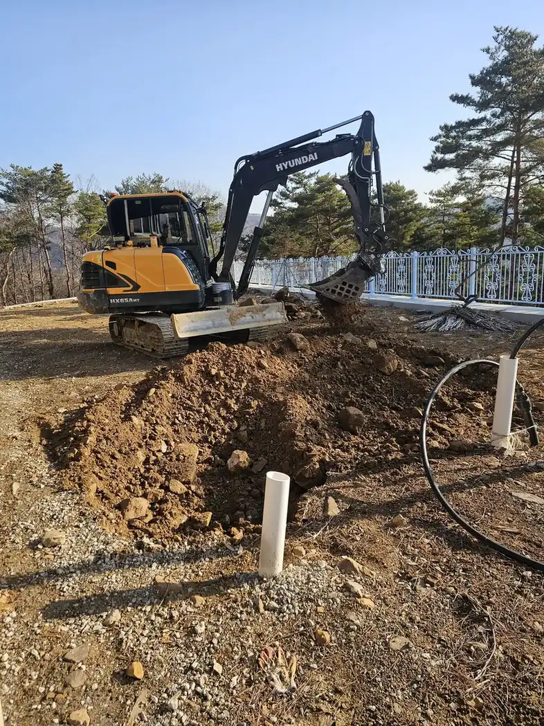 굴착 장비 옆에 배관이 세워진 연못 주변 토목 작업 현장